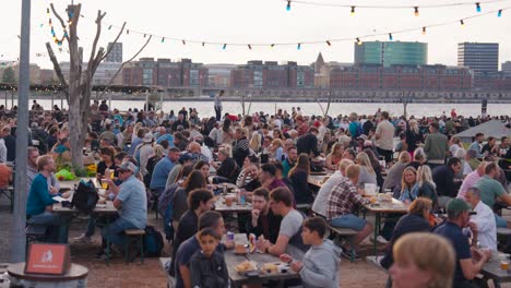 large crowd enjoying an outdoor evening event by the waterfront