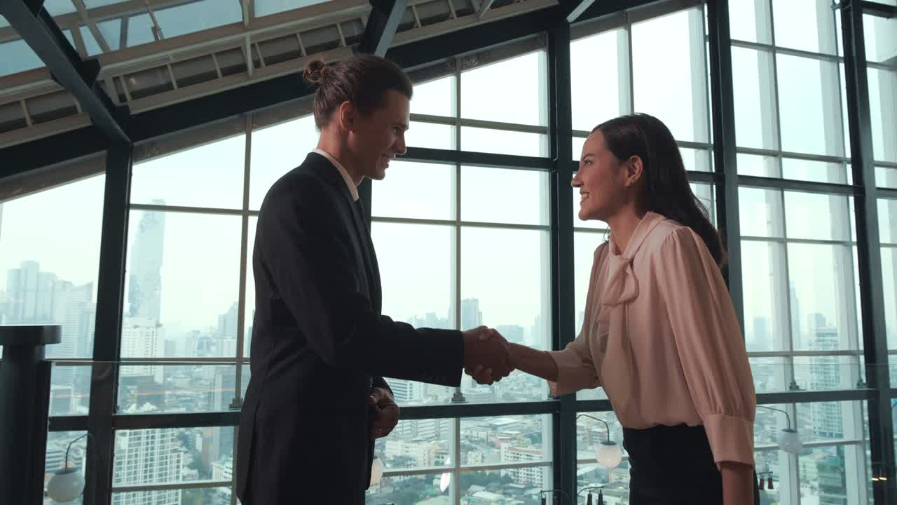 Partner commerciali si stringono la mano in un centro uffici. Sono felici e sorridenti.