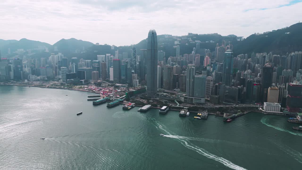 Pemandangan udara panorama gedung pencakar langit dan Pelabuhan Victoria di pusat kota Hong Kong pada hari yang cerah, menampilkan garis langit dan tepi laut yang ikonik