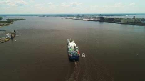 aerial, heavy cargo vessel ship carrying wind turbine blades on small city harbor