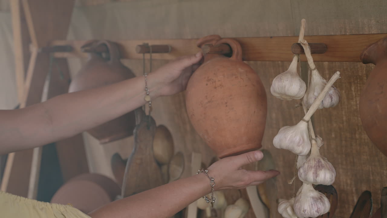 Woman Examining Antique Pottery and Dried Garlic Display