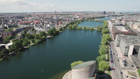 The-Copenhagen-Planetarium-from-above-as-you-fly-over-the-neighboring-lake,-capturing-the-captivating-sight-of-this-architectural-gem-amidst-the-serene-surroundings
