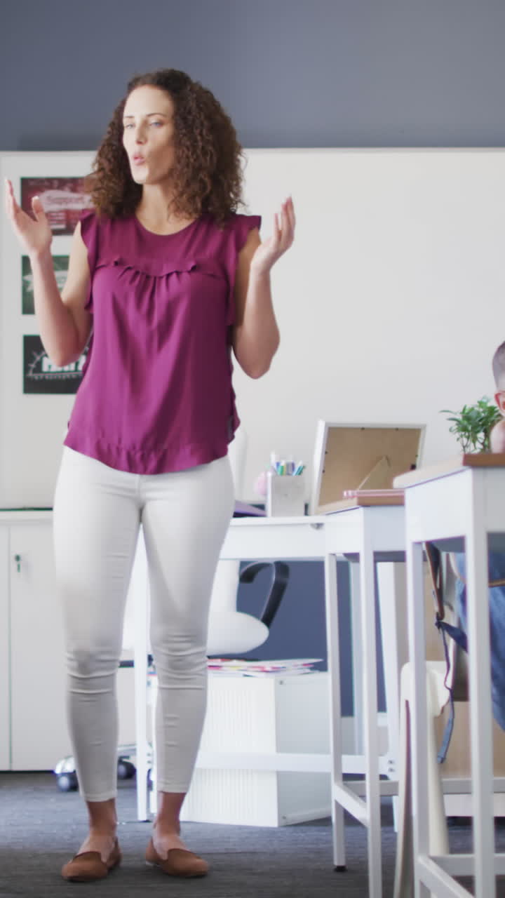 Video of caucasian female school teacher and diverse school children studying in classroom
