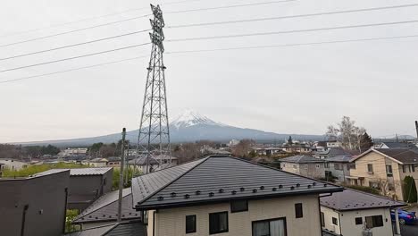 a serene view of mount fuji from kawaguchiko, japan, captured over rooftops with a transmission tower in the foreground