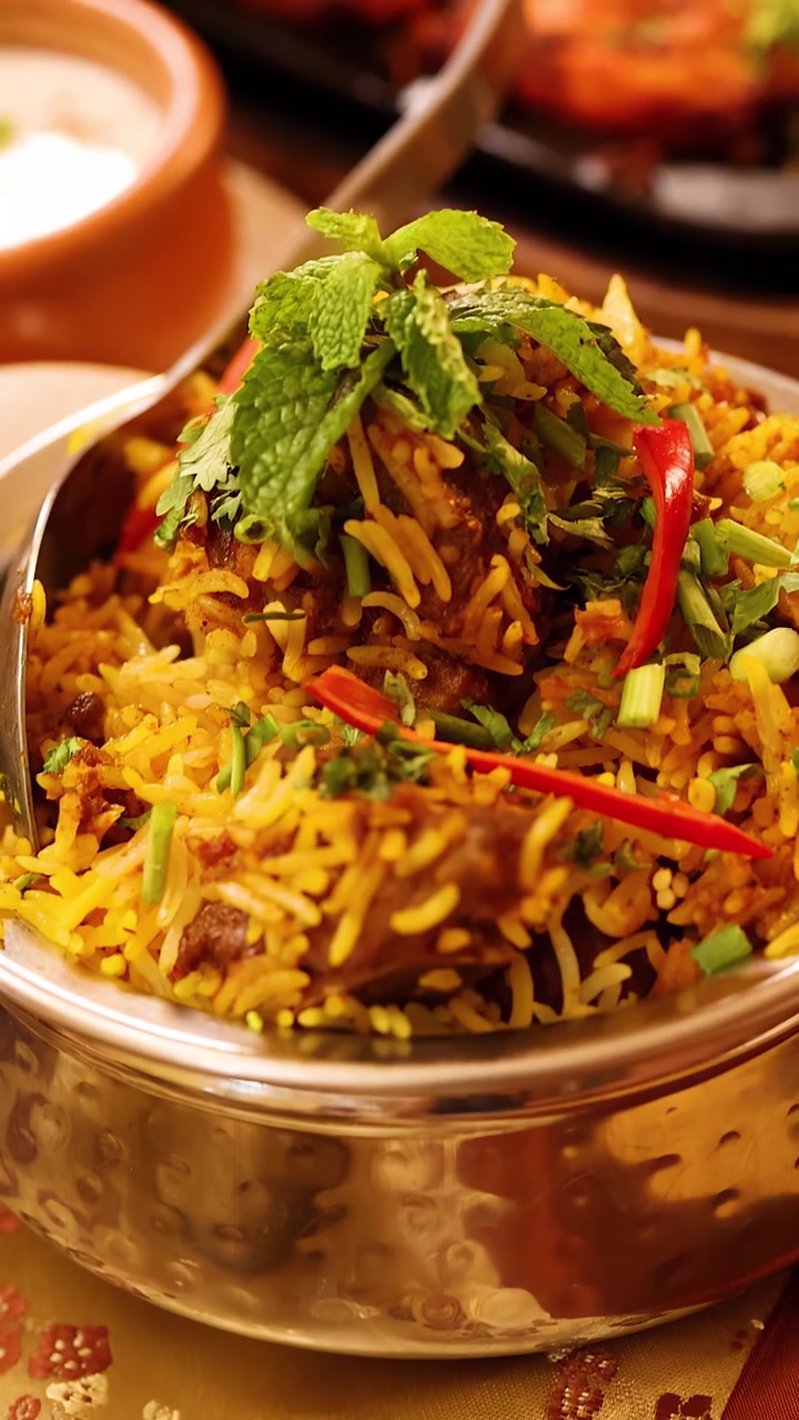 Nærbillede kamera panorerer hen over dampende chicken tikka, lam biryani og traditionelle indiske tilbehørsretter.