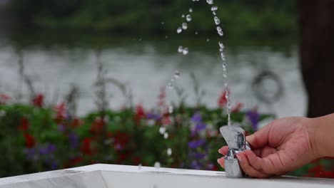 hands turning a tap, increasing water flow