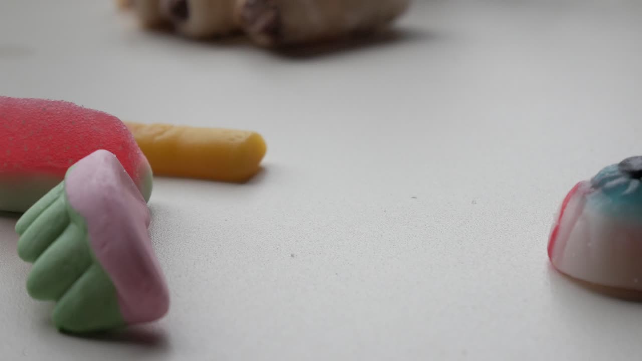 Spooky themed jelies for Trick or Treat celebration. Mixed shapes: denture, veiny, bloody eye, finger. Bright colours on white surface.