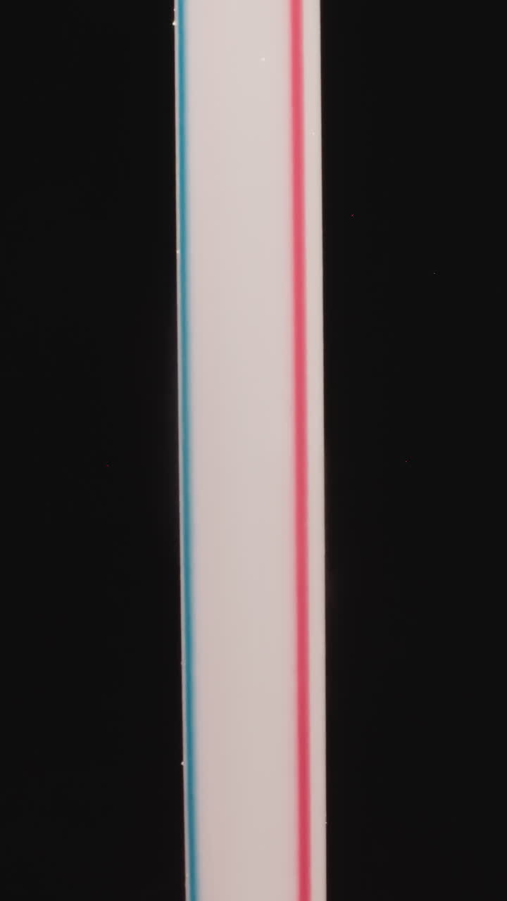 Plastic straw with pink and blue stripes designed for cold drinks on black background. Thin hollow tube for sucking liquid from glass or bottle macro