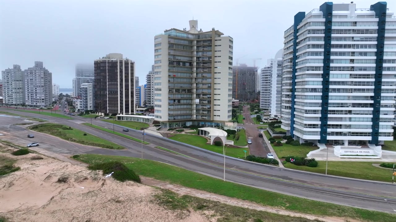 Carretera costera de Punta del Este bordeada por edificios residenciales de mediana y gran altura bajo cielos nublados