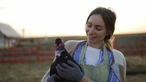 mujer joven sosteniendo un pato doméstico en una granja local