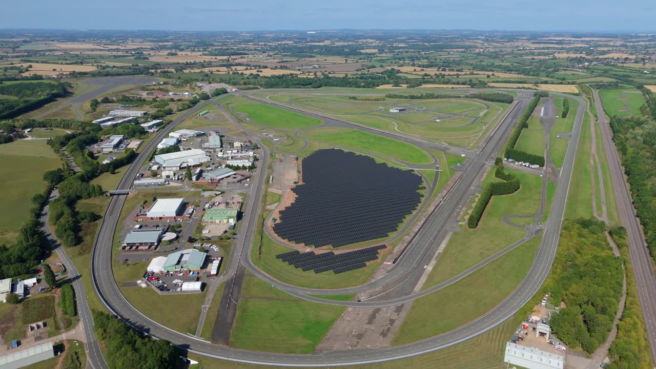 Drone aerial video of automotive testing ground and race track with renewable energy solar panels in England UK industrial landscape