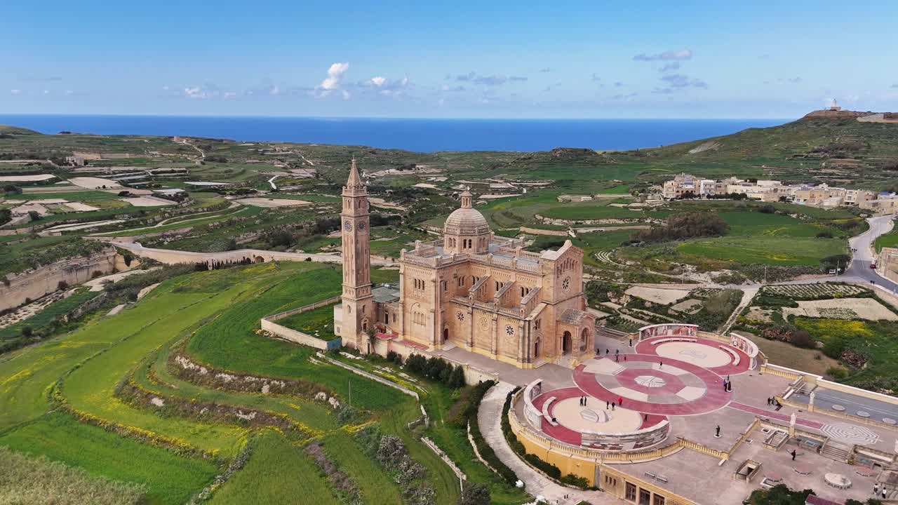 Għarb Gozo Malta'daki Santwarju Bażilika tal Madonna ta’ Pinu, kireçtaşı barok mimarisi ve açık alanlara sahip kırsal bir manzara içinde izole bir şekilde duruyor, havadan drone yörünge tanıtım çekimi