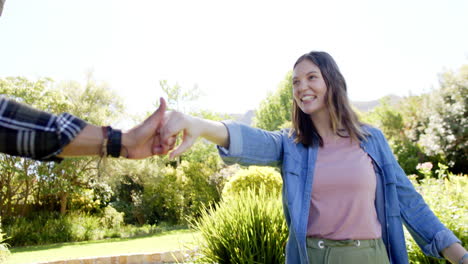 Feliz-Pareja-Diversa-Tomándose-De-La-Mano-Y-Caminando-En-Un-Jardín-Soleado,-En-Cámara-Lenta