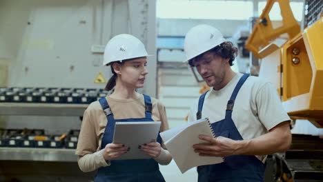 female technician discussing production process with coworker in factory