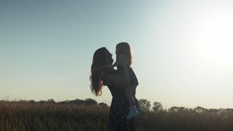 Happy-mother-and-daughter-together-outside-in-summer-sunset-sunlight-having-loving,-family,-motherhood-moment-or-mothers-day-moment-in-cinematic-slow-motion-depicting-joys-of-motherhood