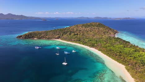 tropical island in ditaytayan, philippines with white sand beach, clear turquoise waters, lush greenery, and yachts anchored in a calm bay surrounded by coral reefs and distant mountainous islands