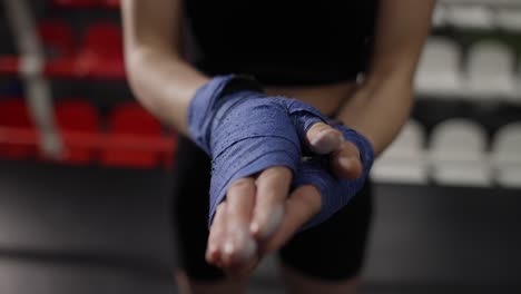 woman dusting powder on her hands wrapped in boxing tapes on boxing ring