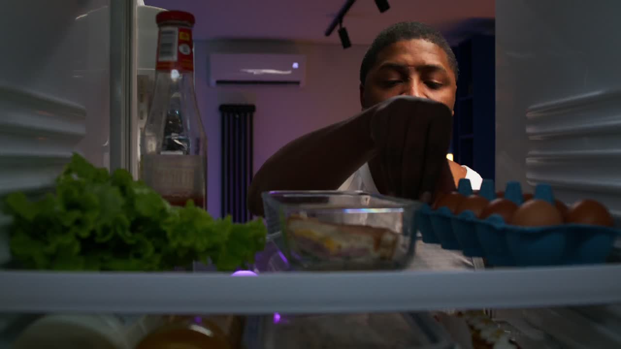 persona mirando en el refrigerador por la noche