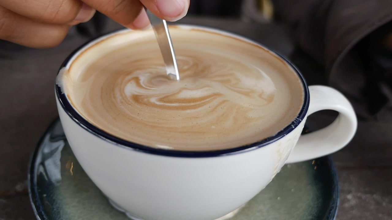 Persona che mescola una tazza di caffè latte