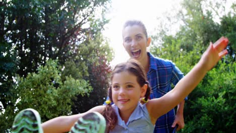 Mother-carrying-daughter-in-wheelbarrow-in-park