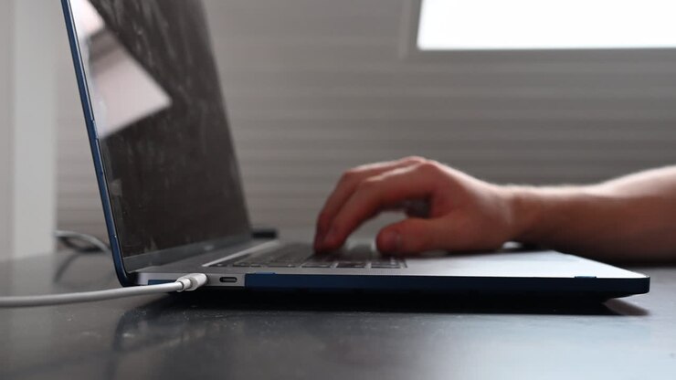 Eine Person tippt auf ihrer Laptoptastatur auf einem Schreibtisch.