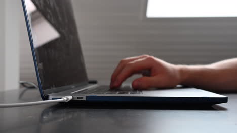 An-electronically-device-user-is-typing-on-his-laptop-keyboard,-on-a-desk