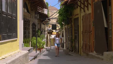 female traveler walking down historical narrow old street in the old town of rhodes, a greek island in the mediterranean, europe