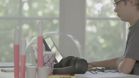 boy sitting at dining room table at home on an ipad