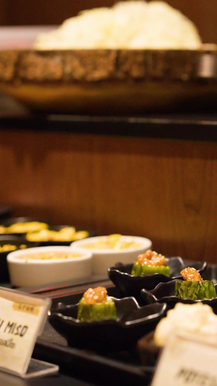 Un cliente prende un piccolo piatto di contorni giapponesi a un buffet di ristorante