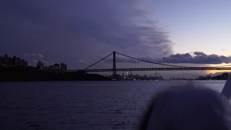 Person-Blickt-Auf-Stürmische-Wolken-Und-Die-Skyline-Und-Brücke-Von-New-York-City,-Während-Sie-Im-Hudson-River-Segelt