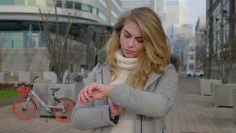 stylish young woman checks her watch, standing in a pavilion