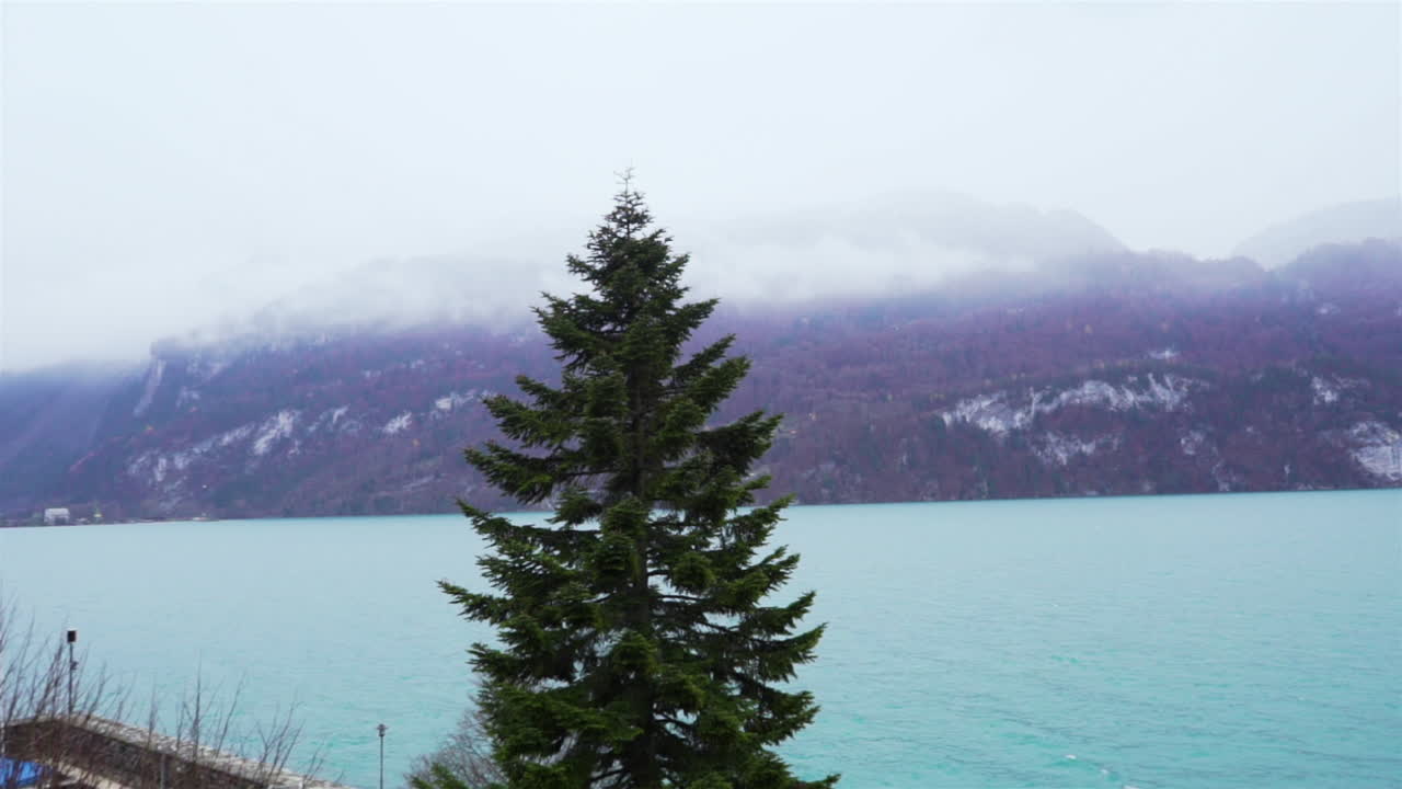 Wide panning shot of the Lake Brienz, in Switzerland, on a foggy day.