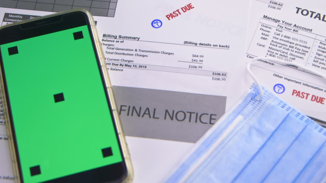 [Camera Used: Canon C300] A slow motion close up of &amp;quot;Past Due&amp;quot; bills, a Covid mask, and a green screen cell phone for your own customization