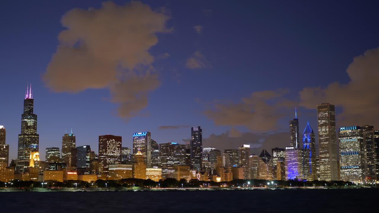 Breathtaking view of Chicago's skyline at twilight. Vibrant city lights reflect on the serene lake, creating a captivating urban scene under a twilight sky, filmed in a steady hyperlapse