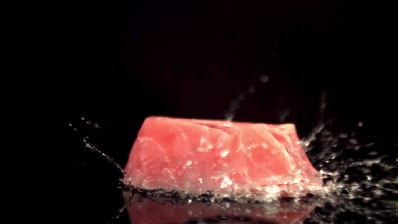 Fresh Raw Tuna Steak Falling and Splashing Water on Black Background