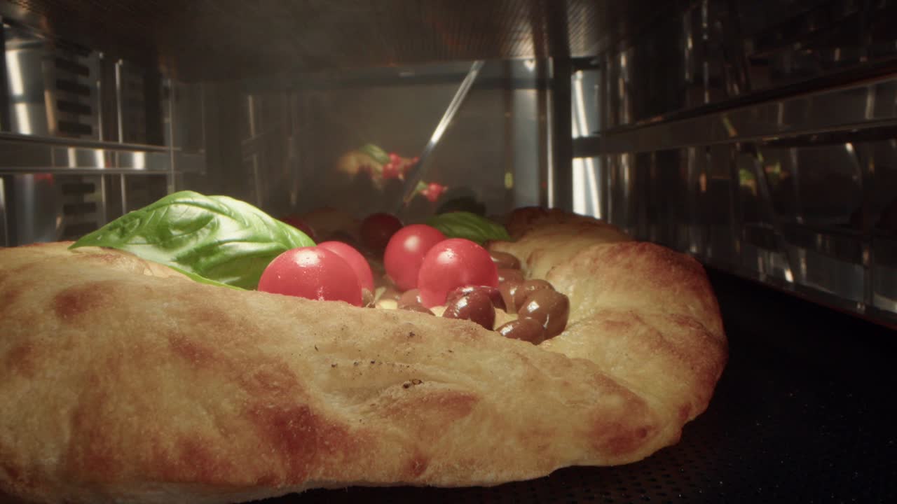 카메라는 맛있는 황금색 갈색 질의 포카치아 피자를 오븐에서 는 클로즈업으로 다시 끌어당니다.