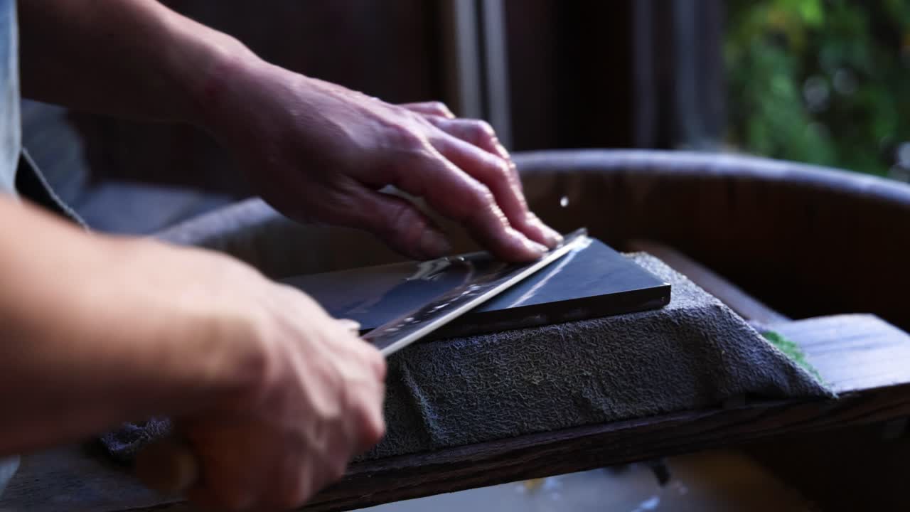 manos meticulosamente afilando un cuchillo en una piedra de afilar