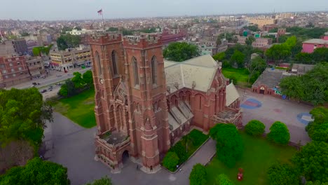 vista aérea de una hermosa iglesia antigua en la ciudad, el tráfico se mueve en el otro lado de la calle de la iglesia, hermosa vegetación alrededor de la iglesia, una bandera en la parte superior de la iglesia