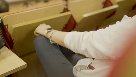 closeup shot of caucasian lady wearing hand jewelry and sitting in classroom