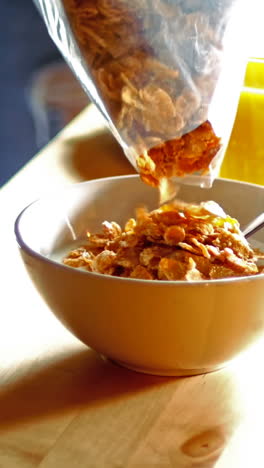 couple pouring cornflakes in bowl in kitchen