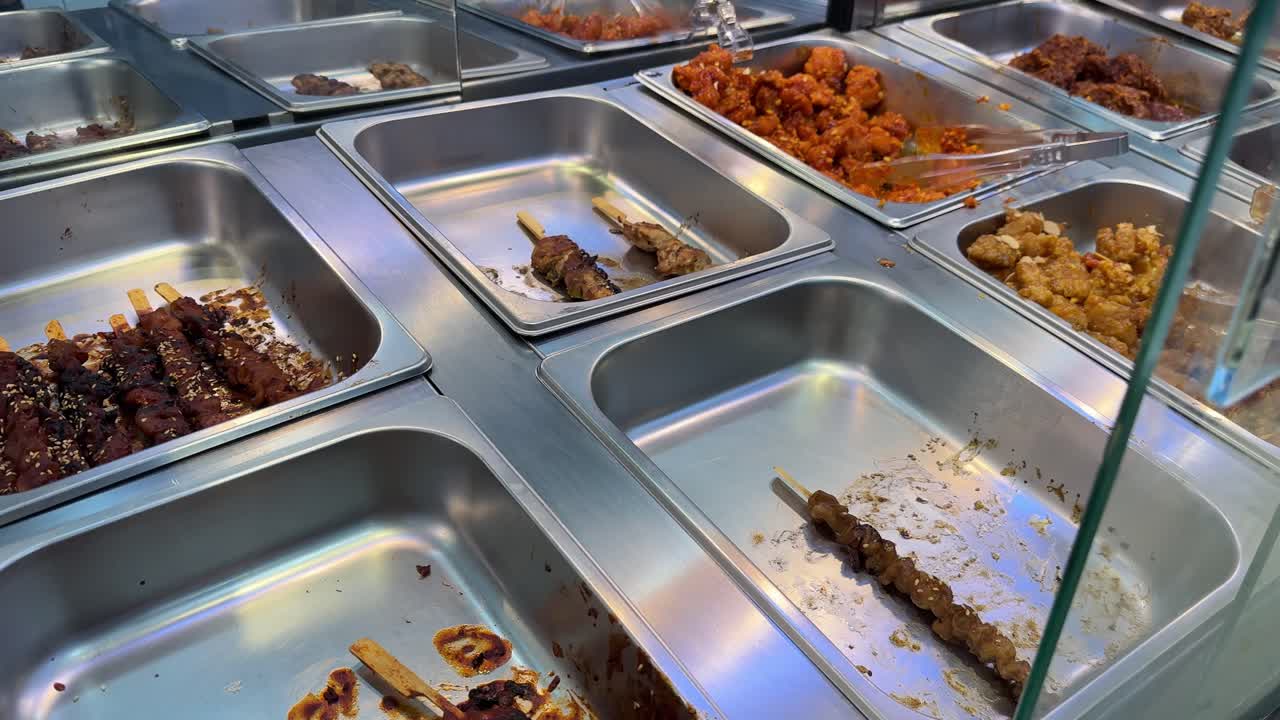 Svuotamento dei vassoi del buffet con pollo fritto e spiedini in un ristorante