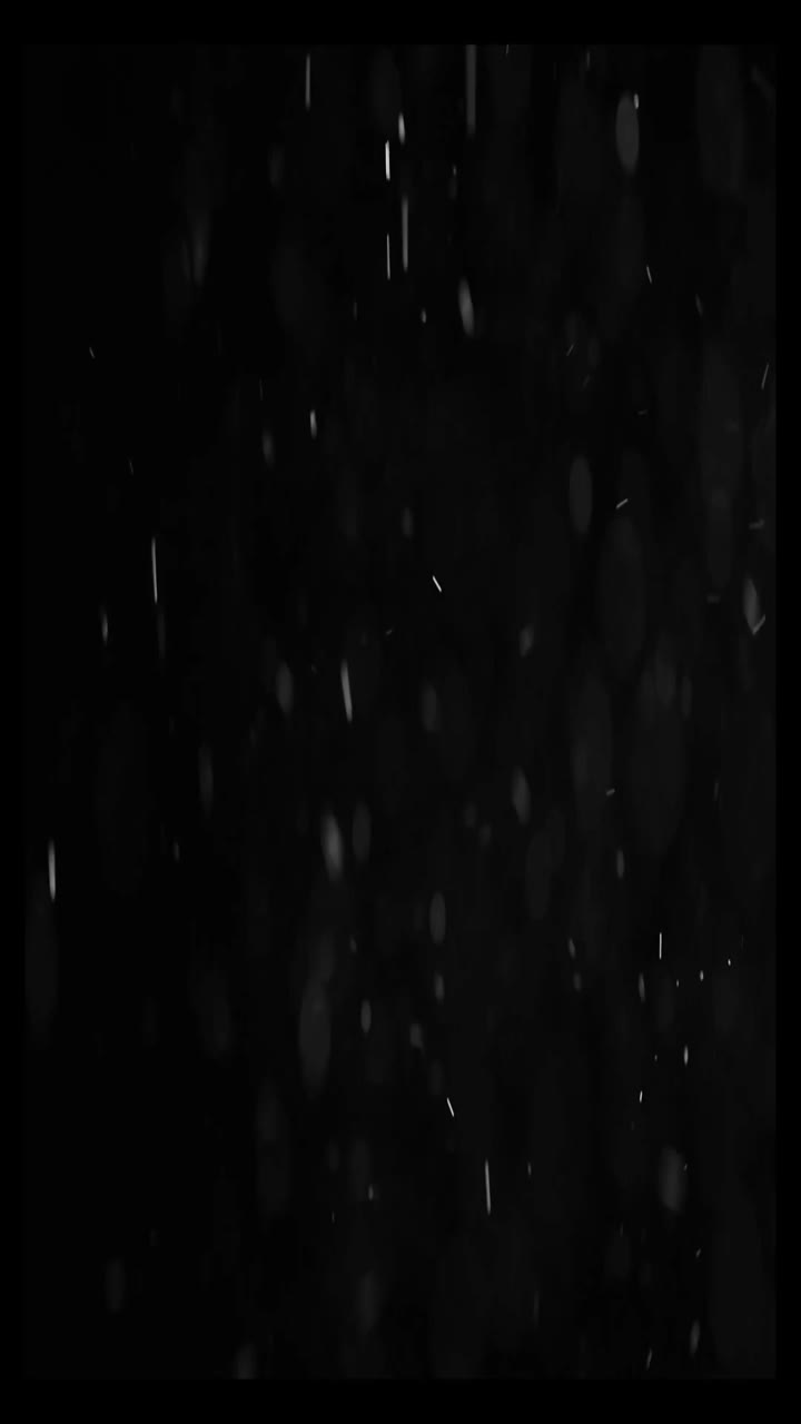 Fallende Schneepartikel auf schwarzem Hintergrund mit Bokeh-Effekt