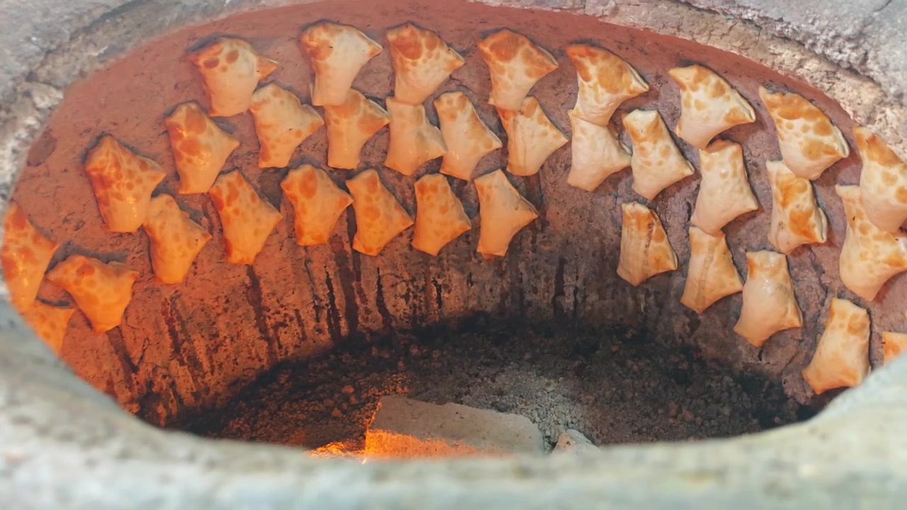 Cottura di Samosa Tradizionali all'Interno di un Forno Tandoor in Argilla