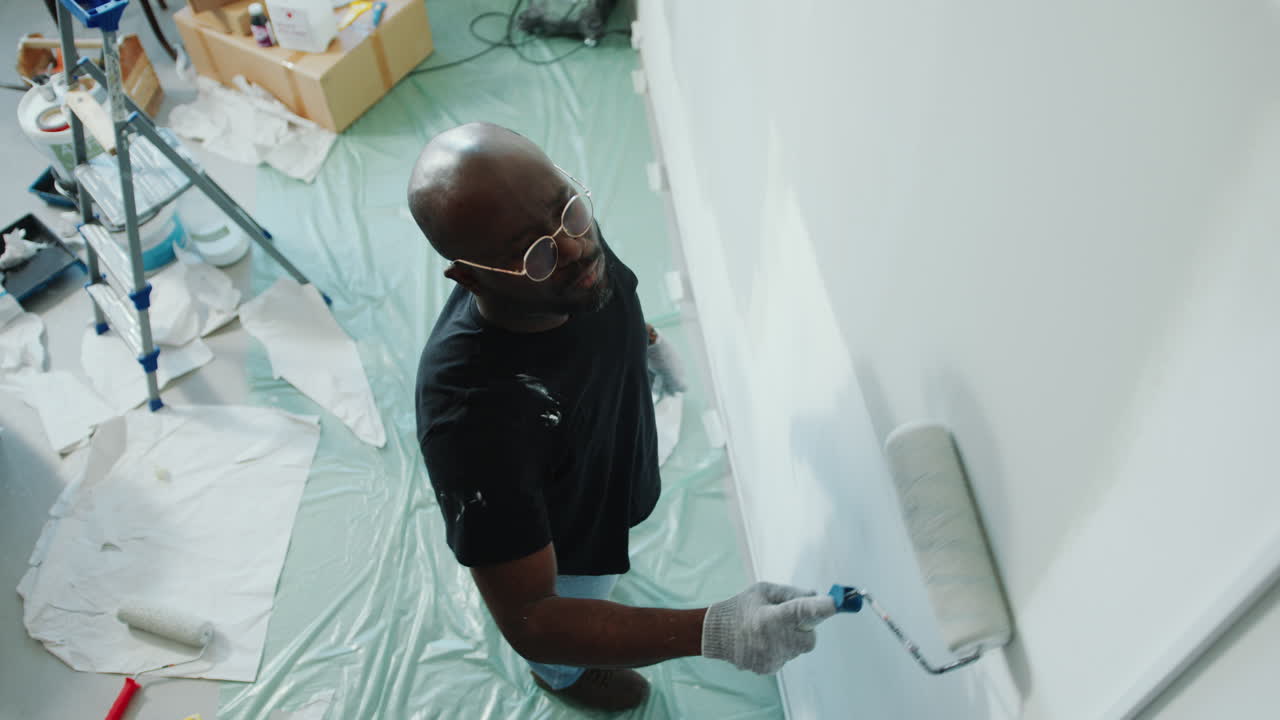 Black Man Painting Wall with Roller during Apartment Renovation