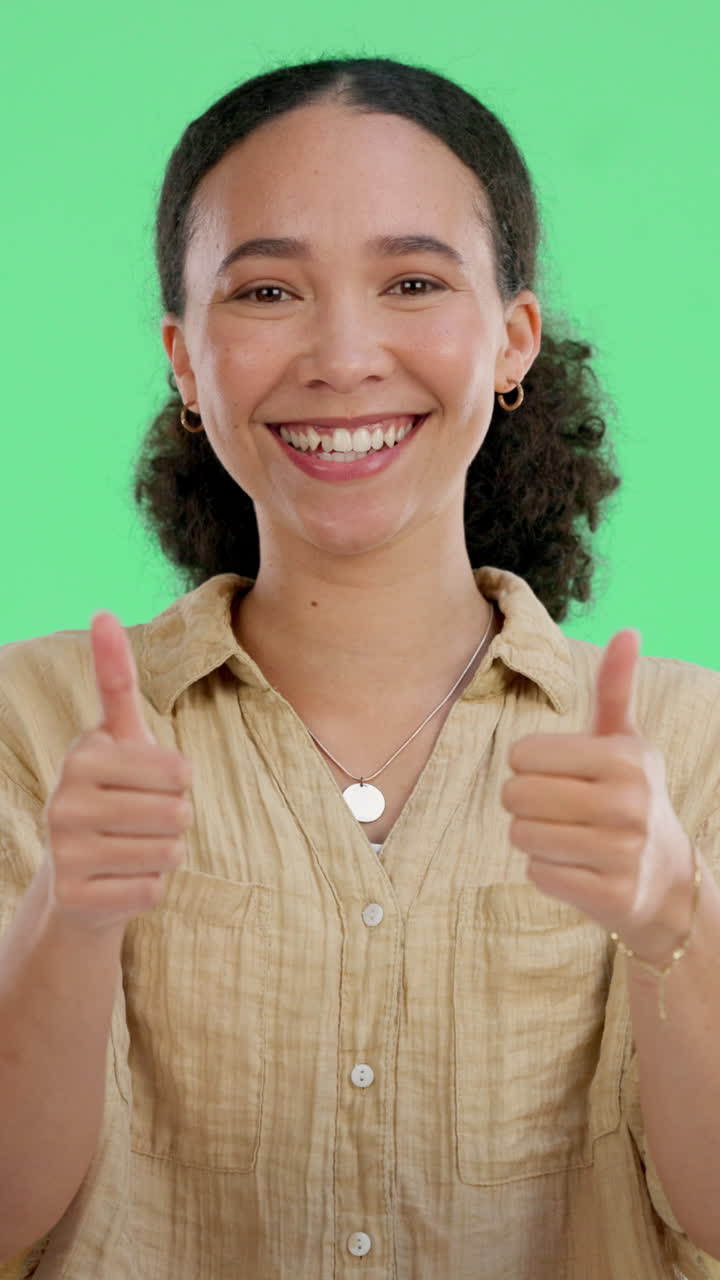 Joven sonriendo y levantando el pulgar sobre fondo verde