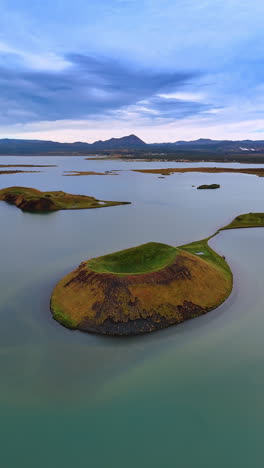 little islands of diverse shapes sticking out of water. remarkable nature of iceland. mountain range at backdrop. vertical video.