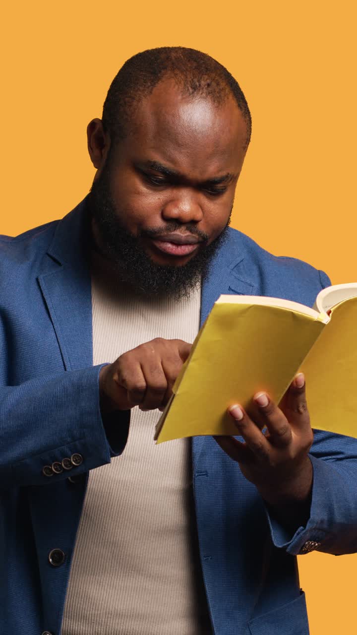 Vertical video Man struggling to read book with small font, pointing finger to words