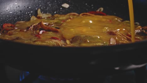 a bubbling, popping and steamy closeup of, vegetables in a skillet, then beaten egg is poured in circles over the top, then two slices of cheese are placed on top