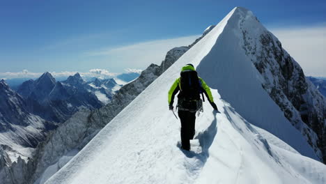 mountaineer ascending a snowy mountain ridge with a panoramic view