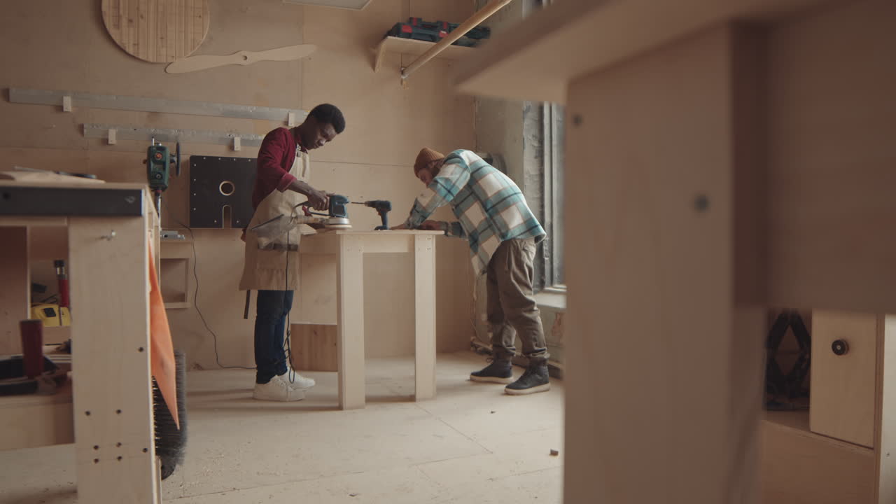Two Diverse Men Polishing Wood Handicraft in Carpentry Workshop